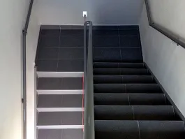 Escalier recouvert de carreaux de céramique gris foncé, avec rampes métalliques
