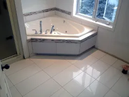 Bain d’angle sur podium avec bande de mosaïque et plancher de céramique blanche
