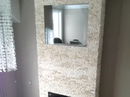 Mur recouvert de pierres décoratives beiges encadrant un miroir